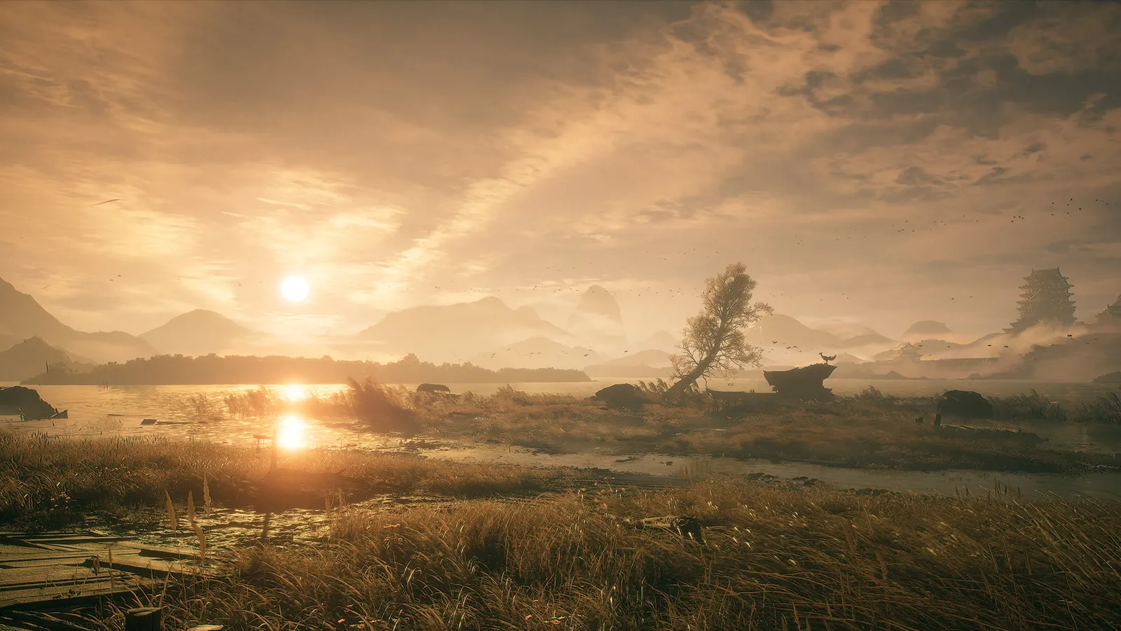 Golden sunset over a reed-lined lake with distant mountains, a lone bent tree and a deer on a rock.