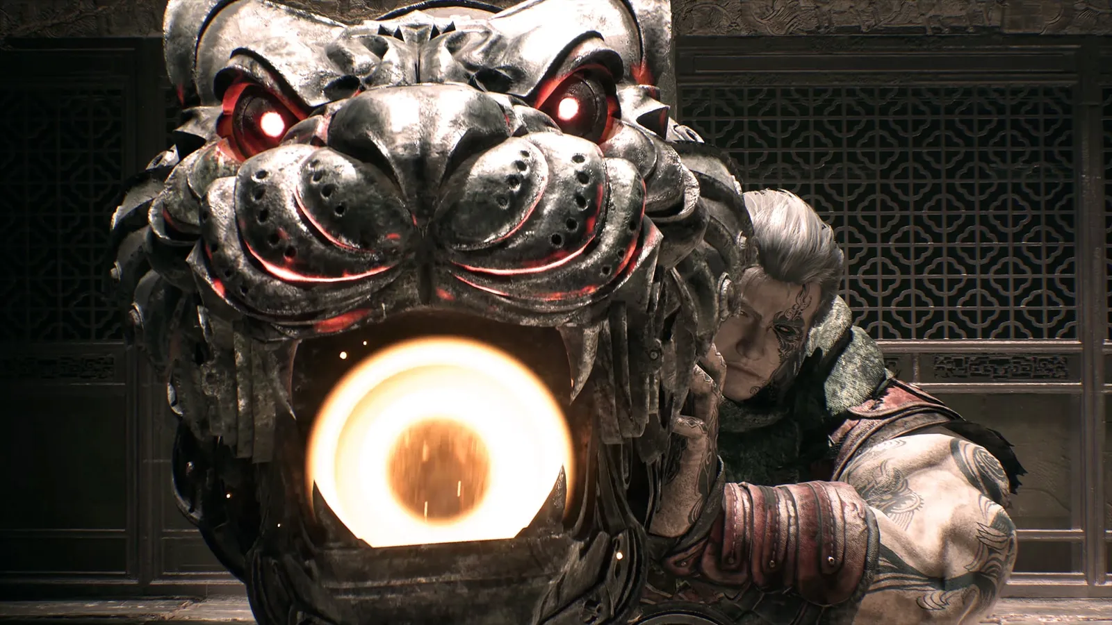 A large metal tiger-face mask with glowing red eyes holds a bright orb in its mouth next to a grey-haired tattooed man in a latticed room.